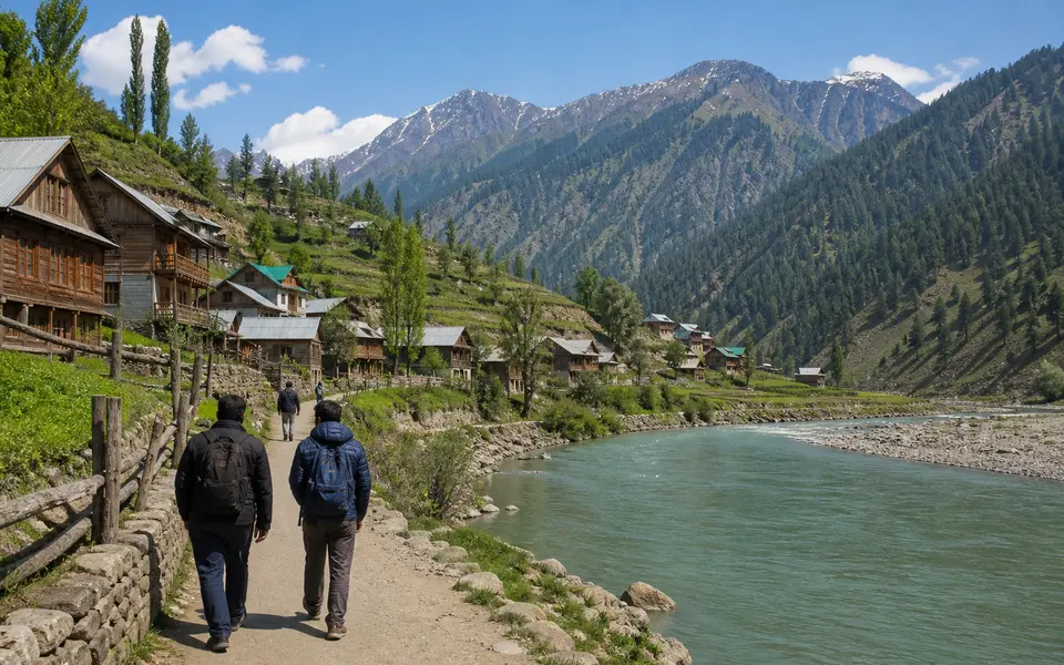 Travellers walking along a safe path beside the Kishanganga River near Dawar, with wooden houses and mountains in the background.