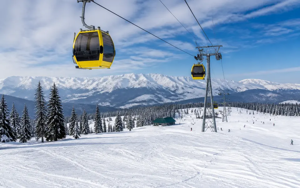Gulmarg Gondola cable cars moving above snow-covered slopes in winter