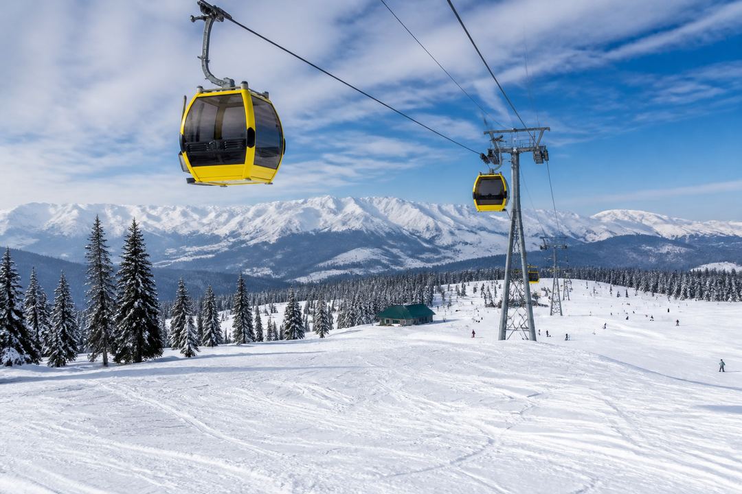 Gulmarg Gondola cable cars moving above snow-covered slopes in winter
