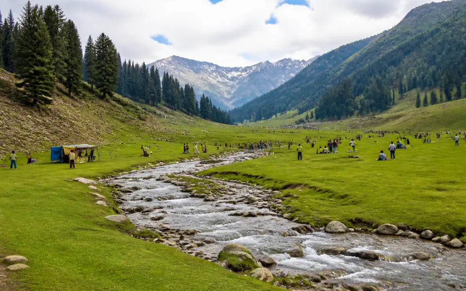 High meadow landscape with a clear stream, green grass and a few visitors, similar to Doodhpathri near Srinagar.