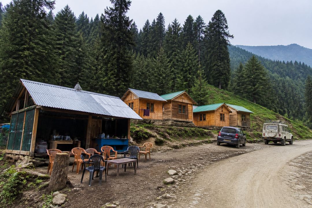 Simple wooden tourist huts and a small roadside tea stall in a forest clearing in Kashmir