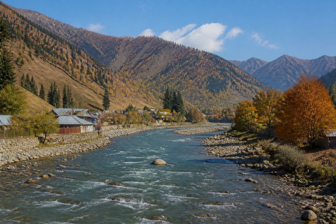 Early autumn view of Gurez Valley with golden-brown slopes, scattered trees and clear skies above the river.