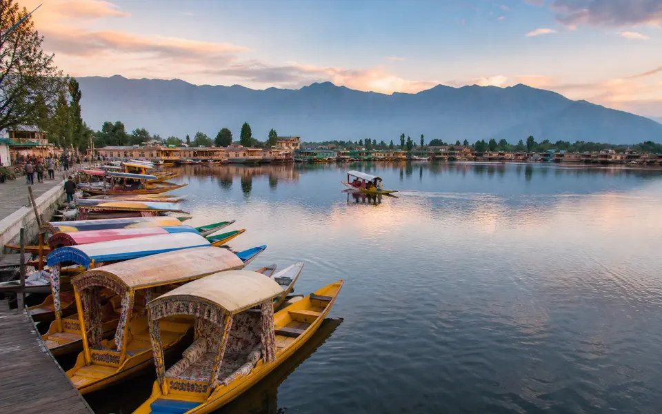 Early morning view over Dal Lake in Srinagar with moored shikaras, houseboats and mountains in the background.