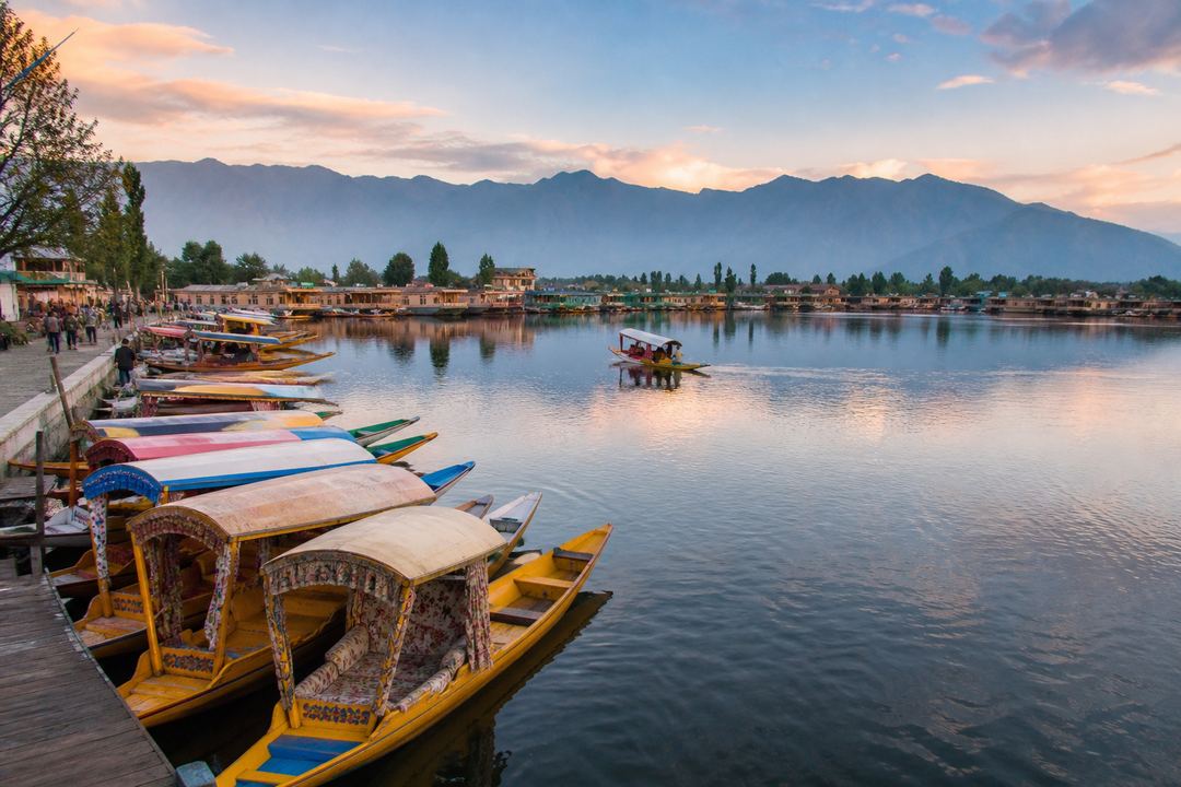 Early morning view over Dal Lake in Srinagar with moored shikaras, houseboats and mountains in the background.