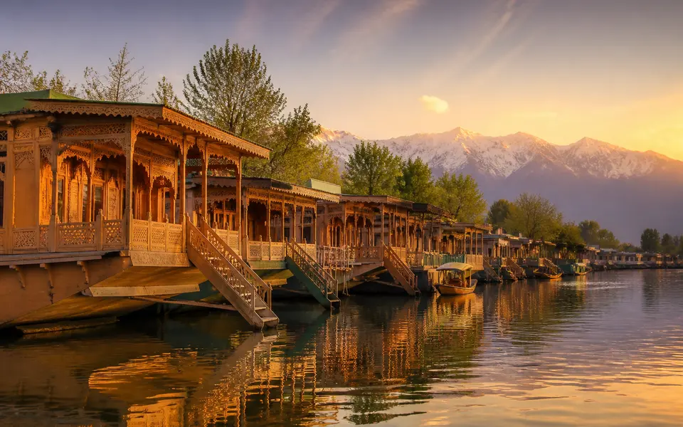 Row of traditional wooden houseboats moored on a calm lake in Srinagar at sunset
