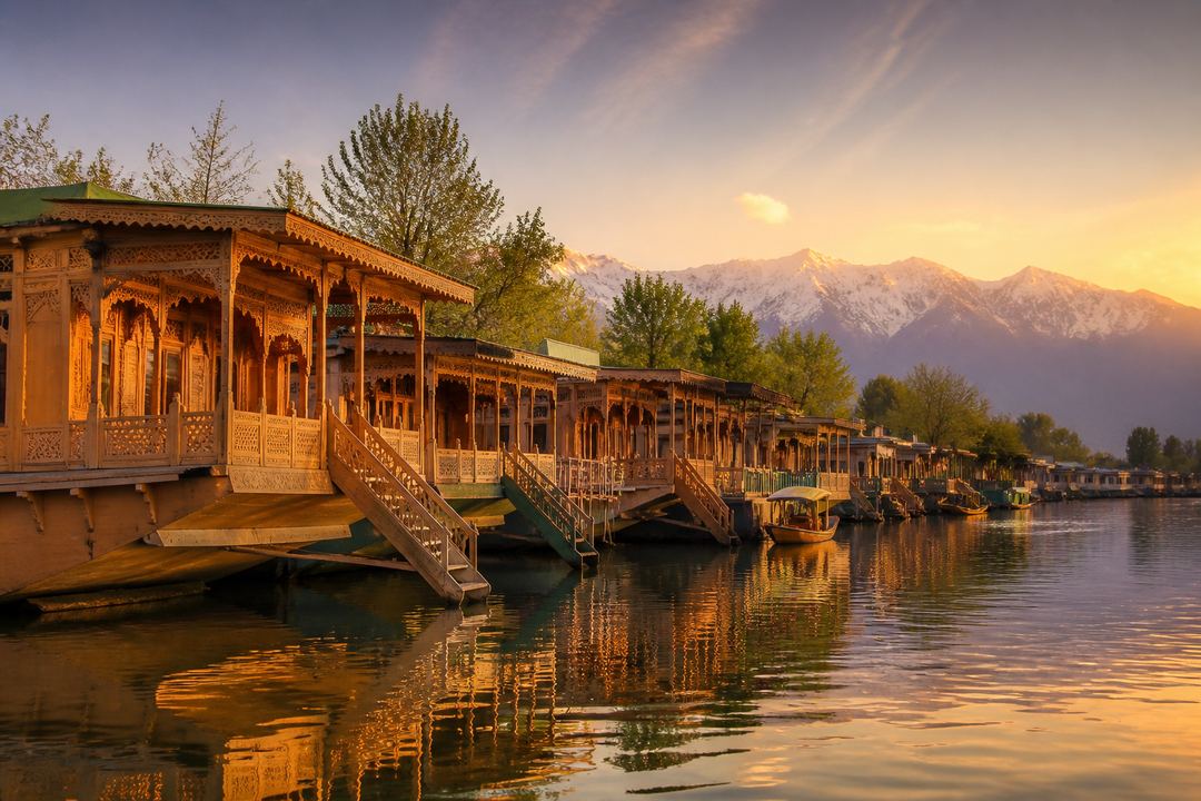 Row of traditional wooden houseboats moored on a calm lake in Srinagar at sunset