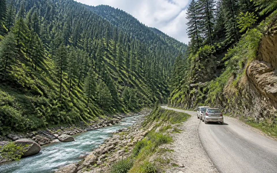 Forested mountain valley with a small road and river, similar to the landscape around Daksum in south Kashmir